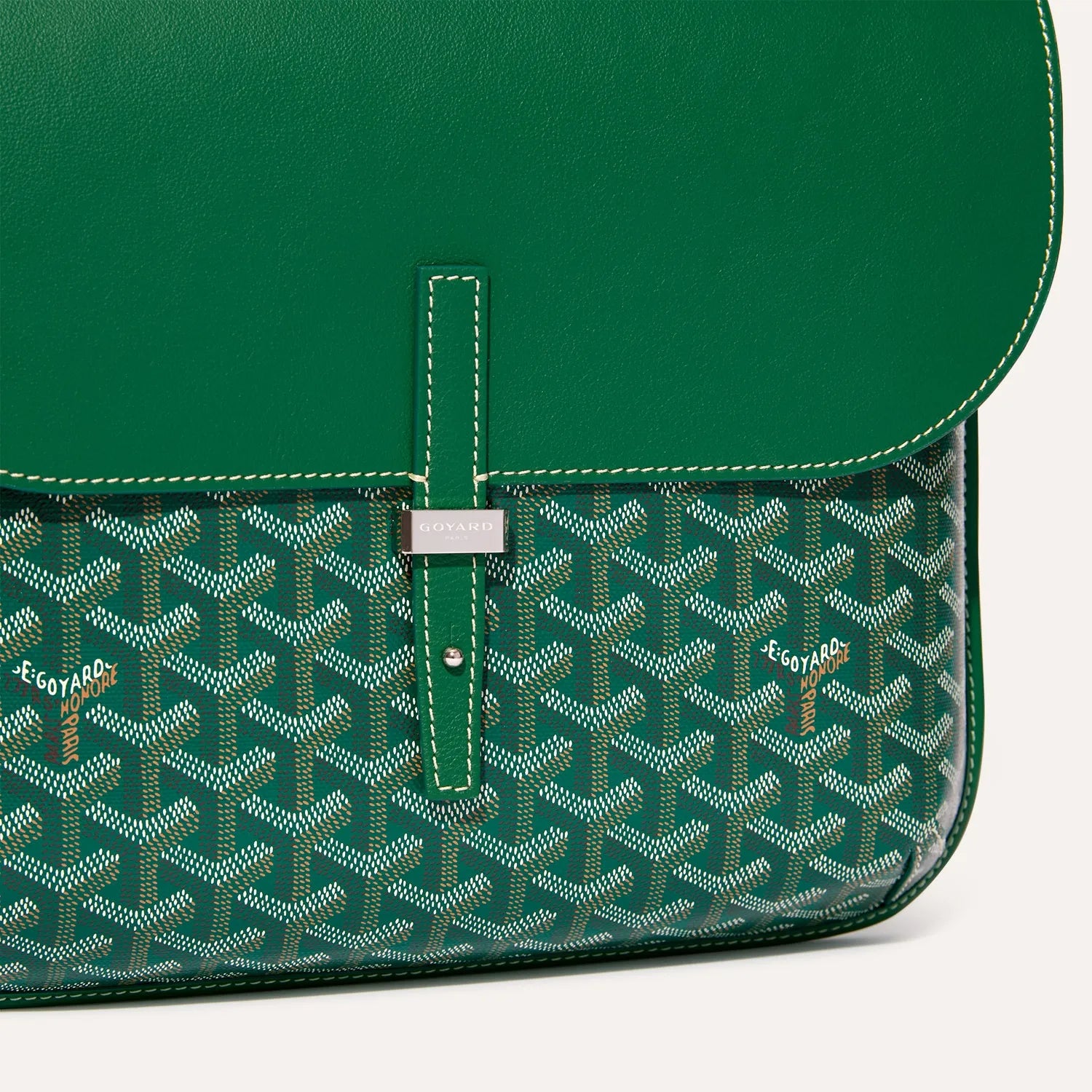 Close up detail of green leather flap and metallic buckle on Goyardine messenger bag